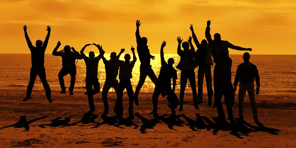 Male friends are having fun at summer and jumping up on the sunset near the sea
